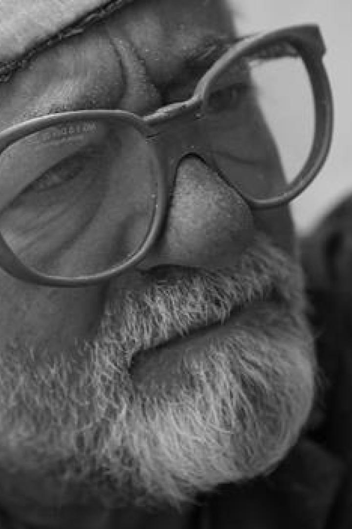 Ein älterer Mann mit Bart und Brille blickt nachdenklich zur Seite.