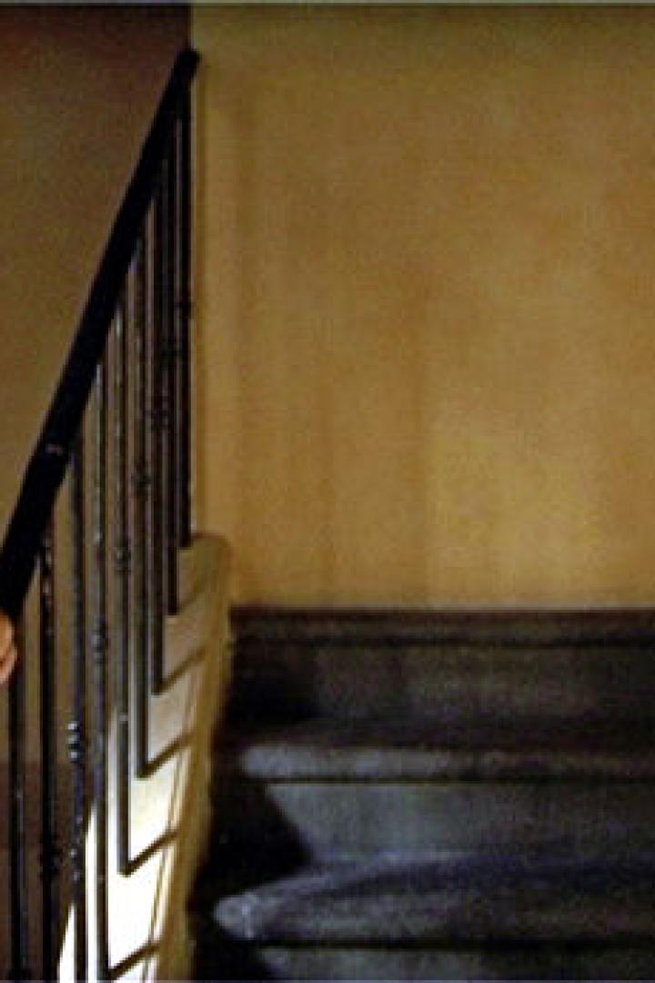 Ein älterer Mann geht eine Treppe hinauf und hält sich am Geländer fest.