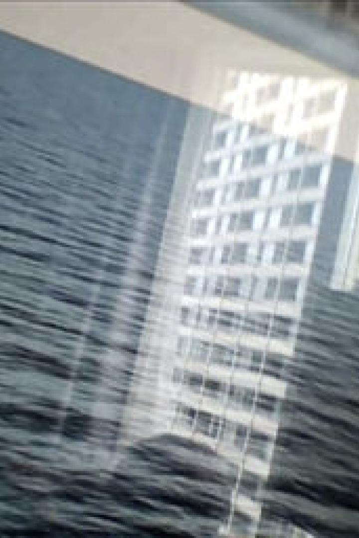 Ein Foto zeigt eine Meeresoberfläche mit der Spiegelung eines Gebäudes.