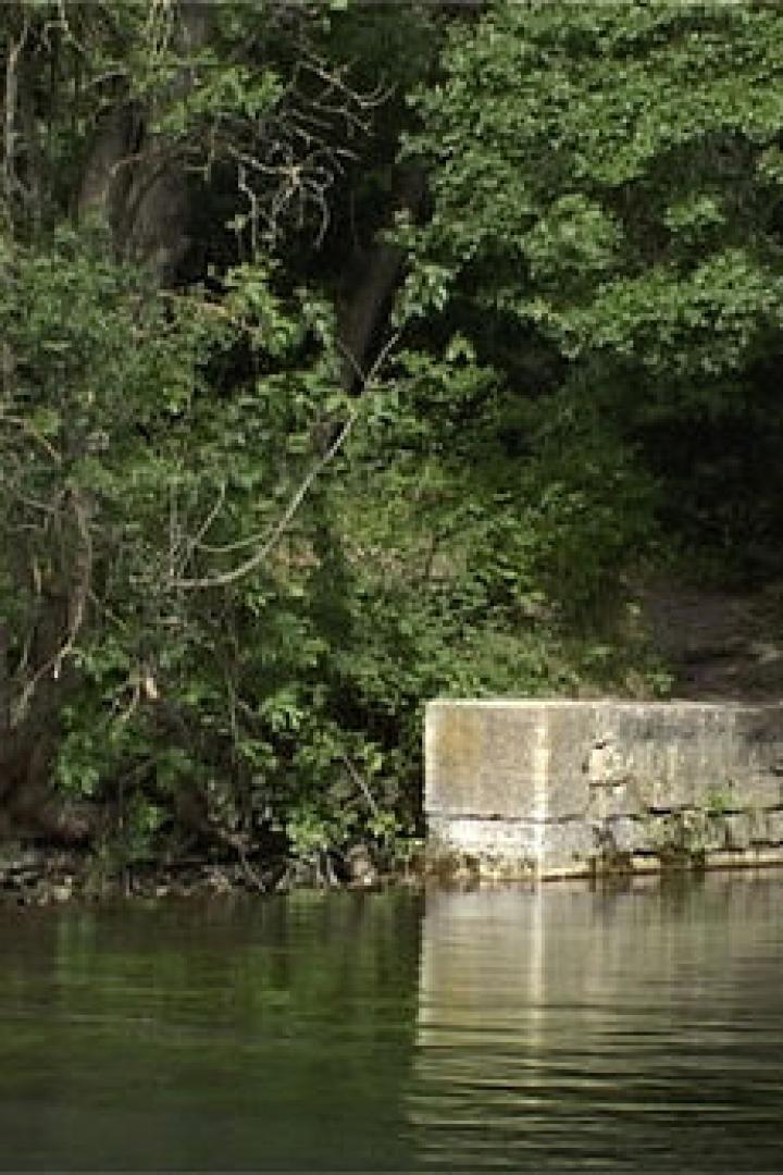 Ein Betonblock steht am Ufer eines Flusses, umgeben von Bäumen.
