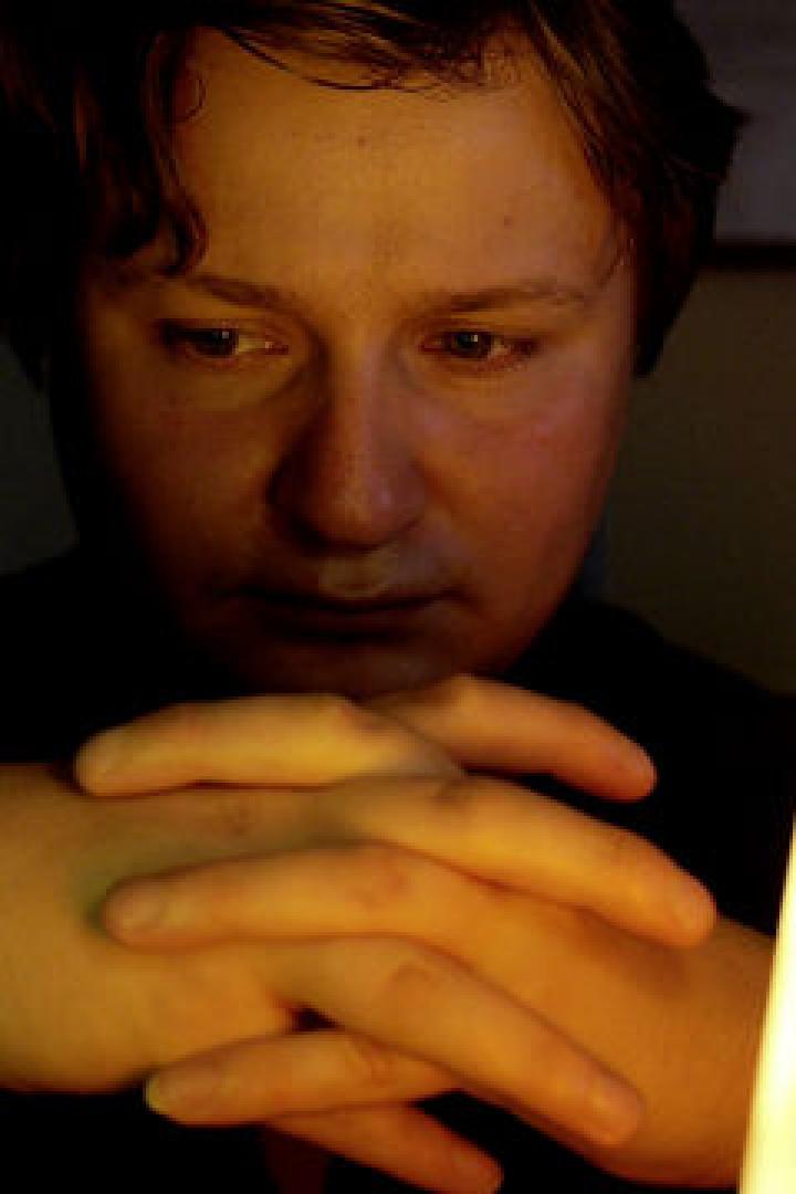 Ein Mann sitzt zwischen zwei Lavaleuchten und blickt nachdenklich nach unten.