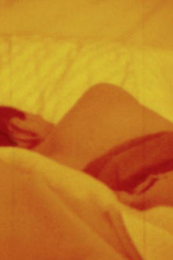 Eine Person liegt in einem orangefarbenen Bett und schläft.