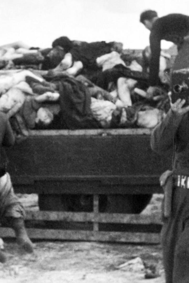 Ein Soldat filmt, während andere Leichen von einem Lastwagen tragen.