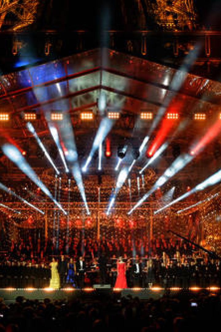 Eine Open-Air-Veranstaltung mit Orchester und Sängern vor dem Eiffelturm.