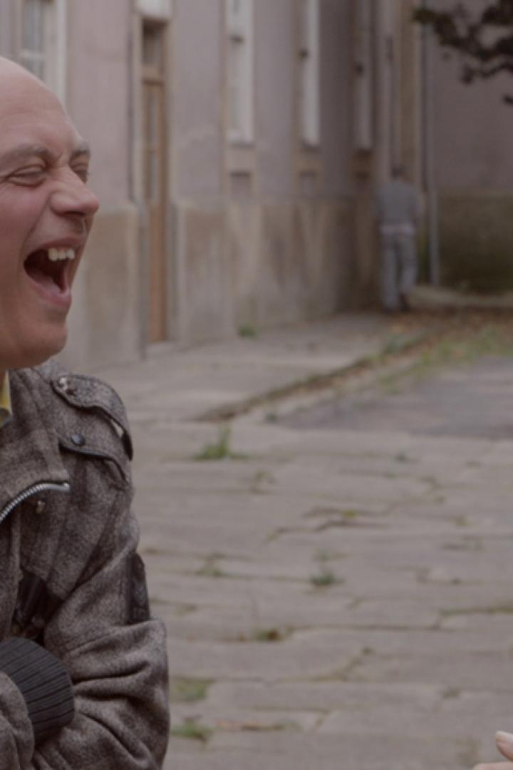 Ein Mann lacht, während ein anderer mit Brille ihn ansieht.