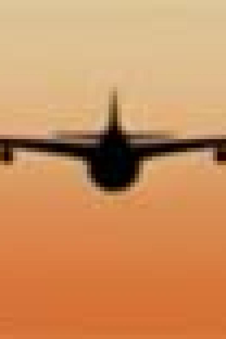 Die Silhouette eines Flugzeugs vor einem orangefarbenen Himmel.