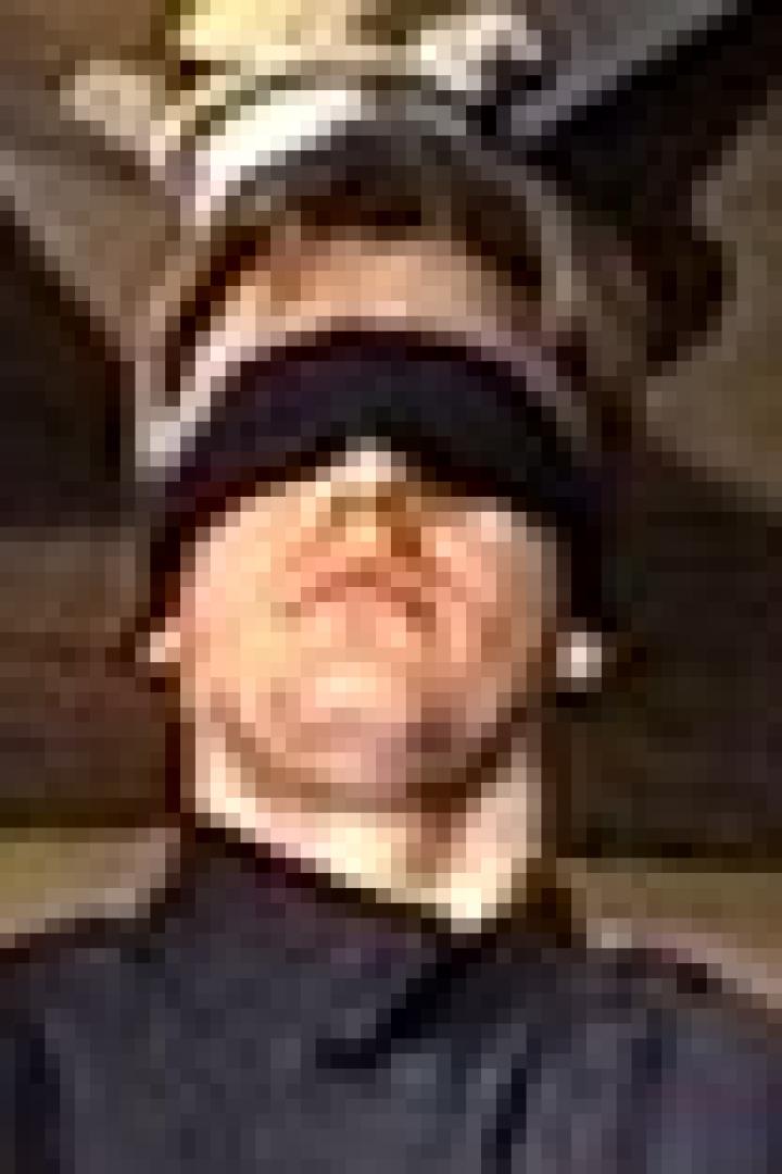 Ein Mann mit verbundenen Augen steht unter einem Holzbalken.