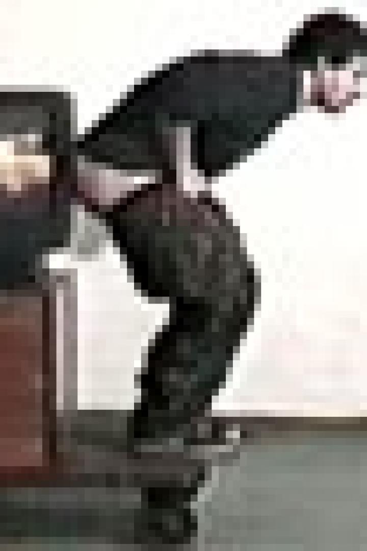 Ein Mann steht auf einem Rollwagen mit einem Fernseher und entblößt sein Gesäß.