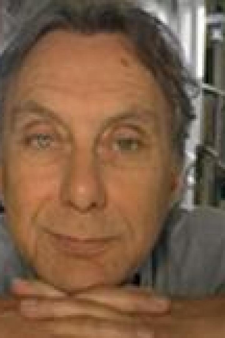 Ein älterer Mann mit hellen Augen und grauem Haar lächelt in die Kamera.