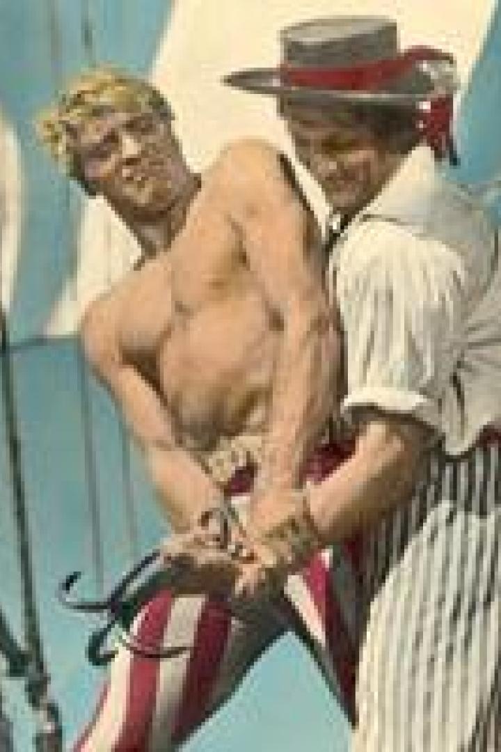Zwei Männer in gestreiften Hosen stehen an Bord eines Schiffes und ziehen an einem Seil.