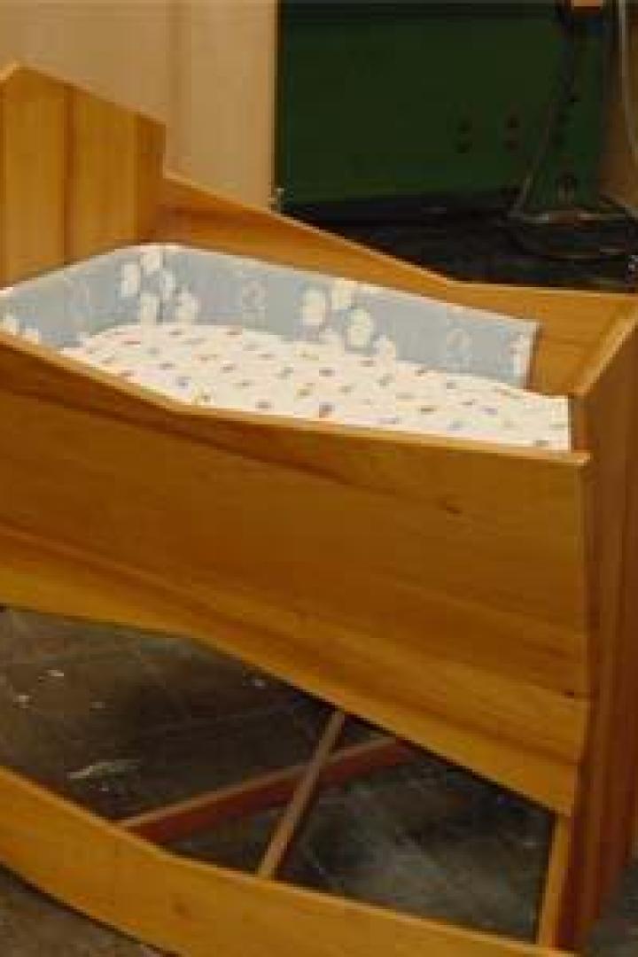 Eine hölzerne Babywiege mit einer gepolsterten Innenausstattung.