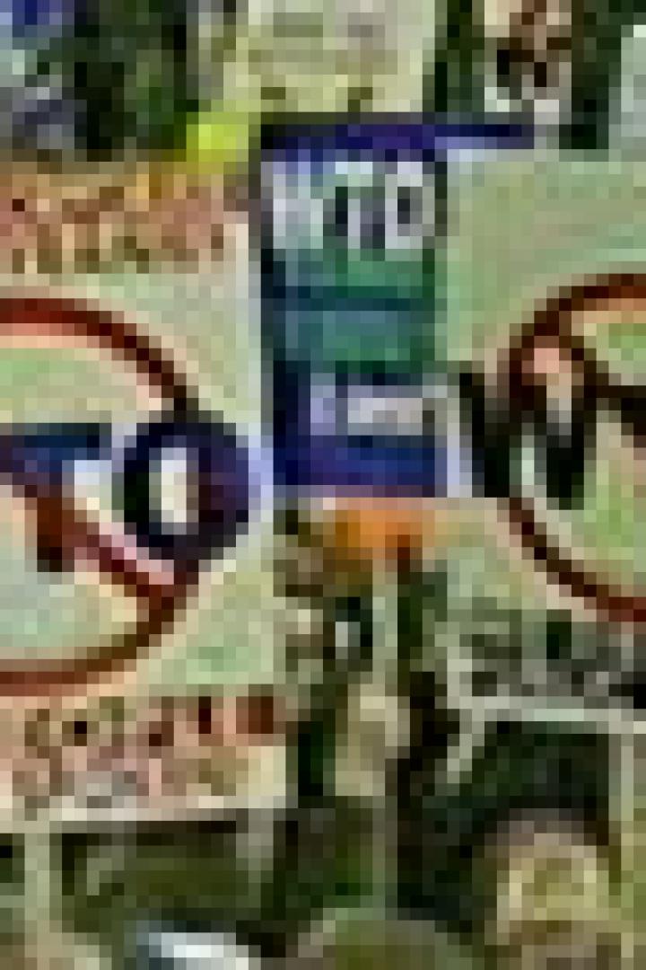 Zwei Schilder mit der Aufschrift „WTO“ und einem durchgestrichenen Kreis werden auf einer Demonstration gezeigt.