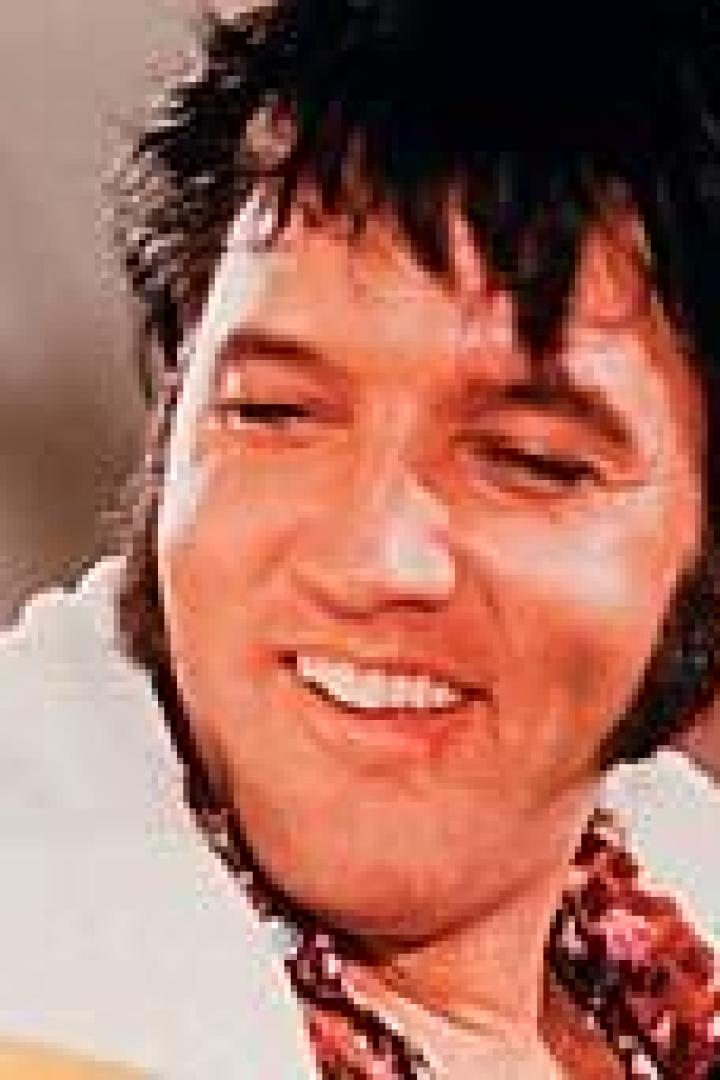Ein lächelnder Elvis Presley mit einem Handtuch um den Hals.