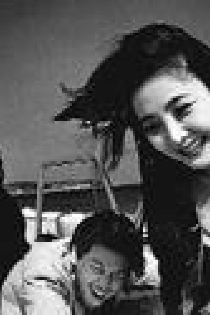 Drei Personen posieren lächelnd für ein Schwarzweißfoto im Freien.