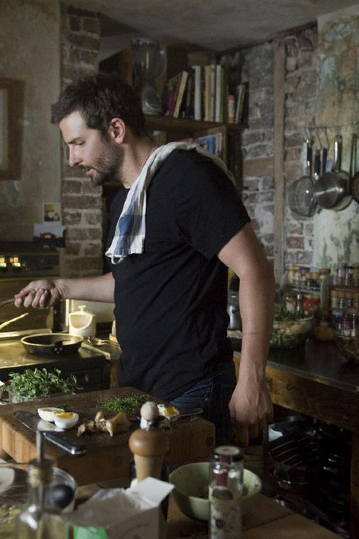 Ein Mann kocht in einer rustikalen Küche mit Zutaten auf dem Tisch.