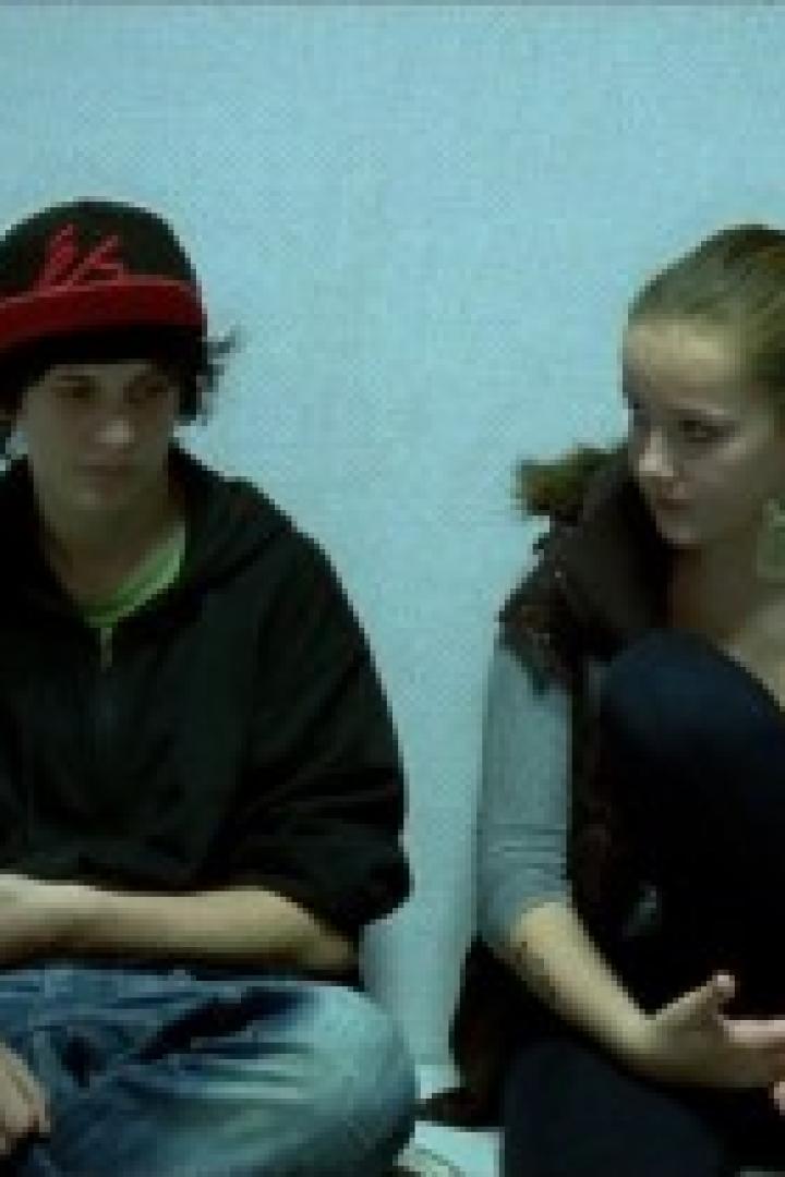 Zwei junge Menschen sitzen nebeneinander auf dem Boden.