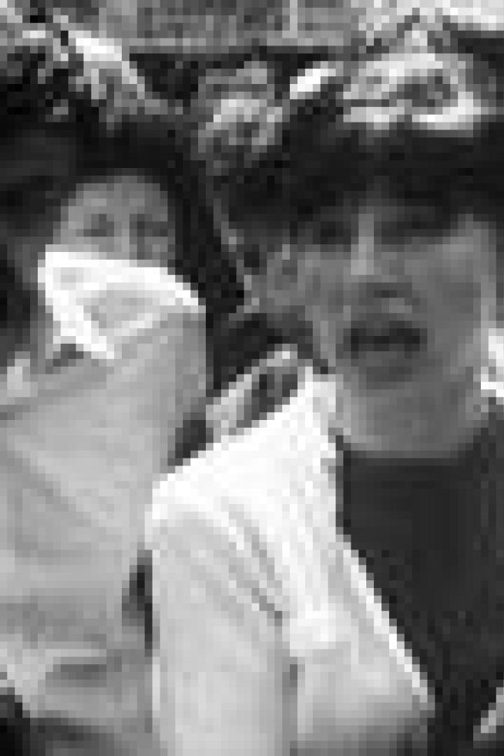 Eine Frau mit dunklen Haaren spricht in einer Menschenmenge mit zwei Männern.