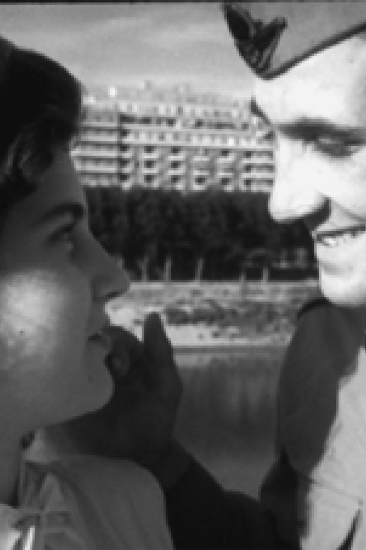 Ein junger Soldat und eine junge Frau stehen einander gegenüber und lächeln sich an.