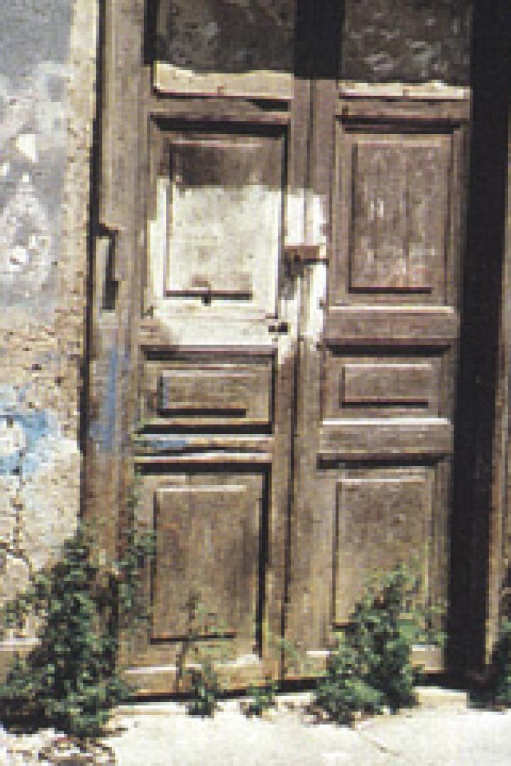 Ein älterer Mann geht an einer verfallenen Tür vorbei.