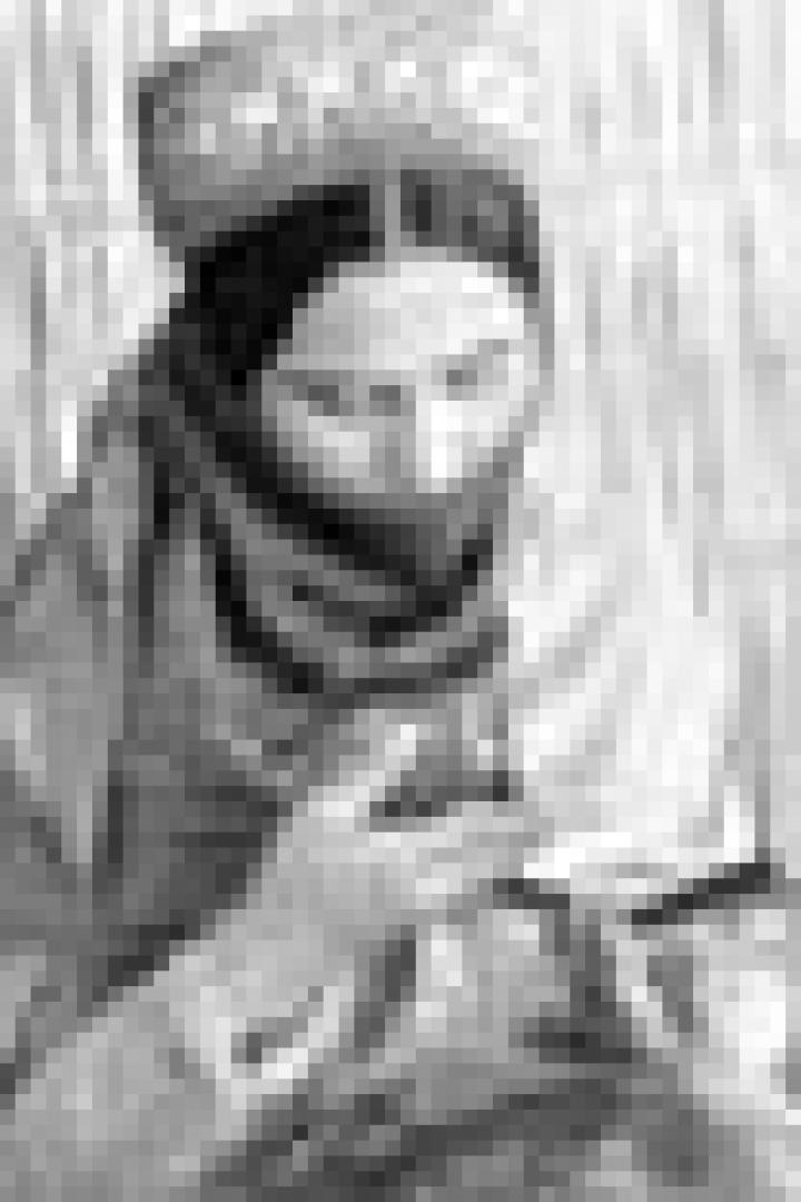 Eine Frau mit traditioneller Kopfbedeckung liest ein Buch.