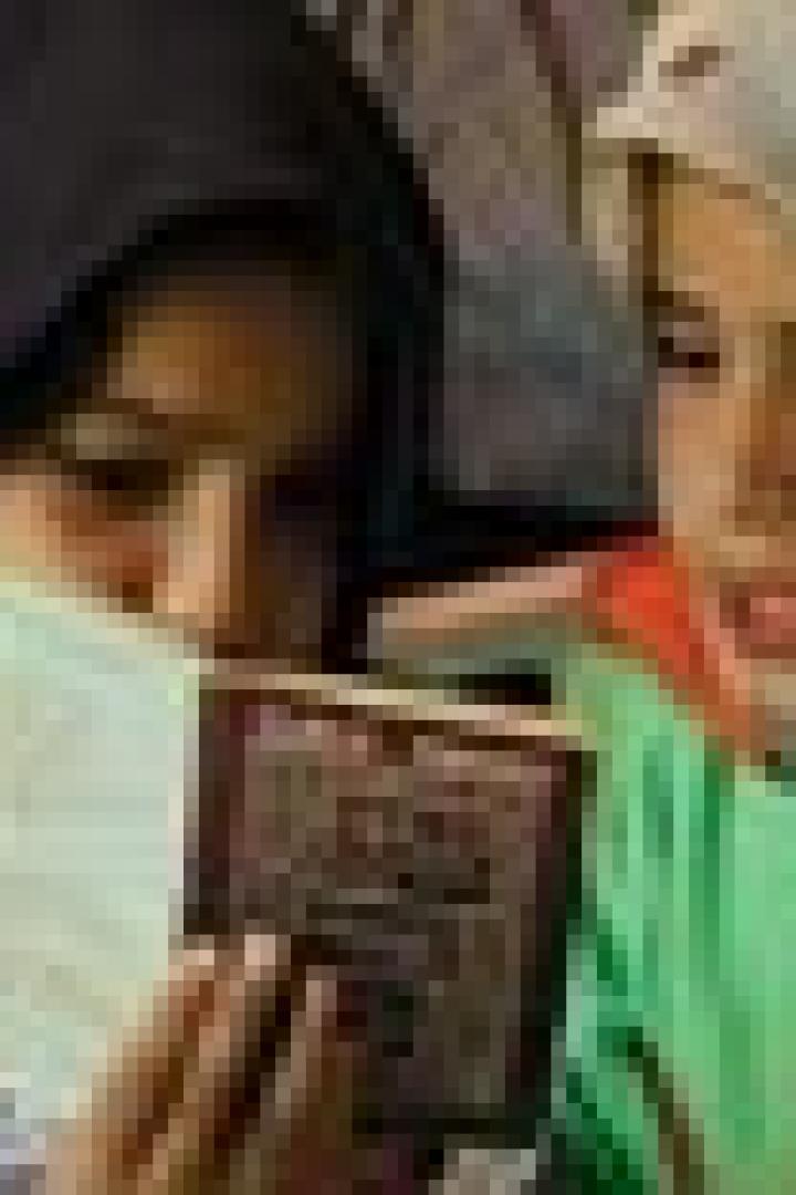 Zwei junge Mädchen lesen gemeinsam in einem Buch.