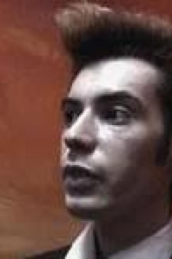 Ein Mann mit hochgestyltem Haar blickt zur Seite.