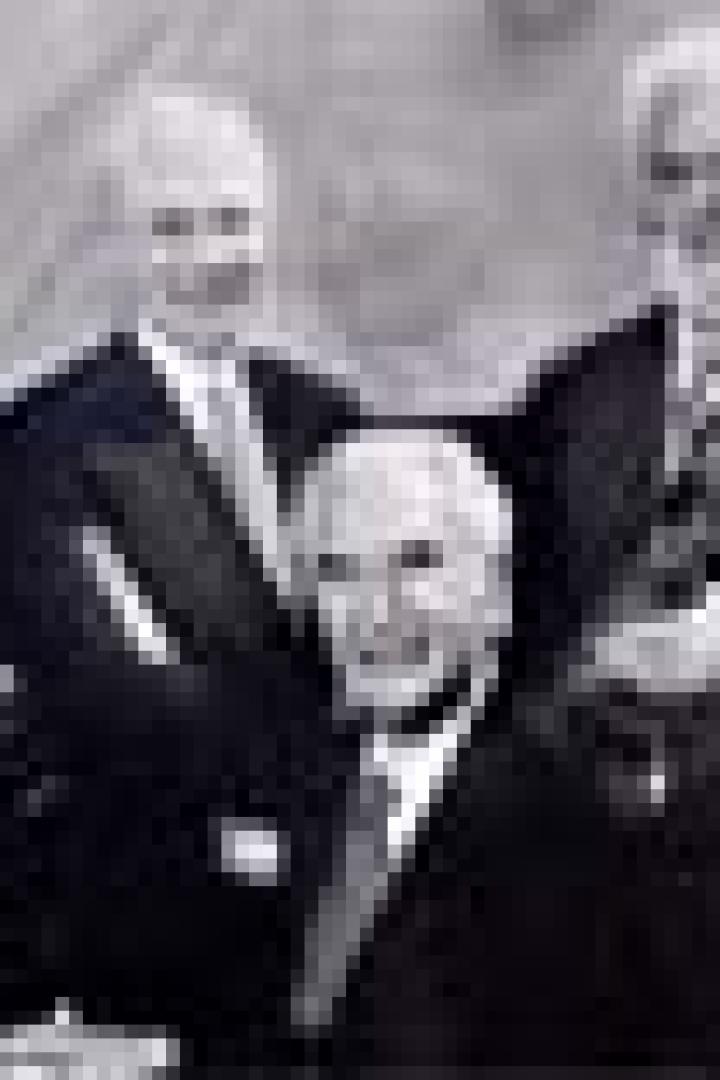 Eine Schwarzweißaufnahme von vier älteren Herren in Anzügen, die ein Streichquartett bilden.