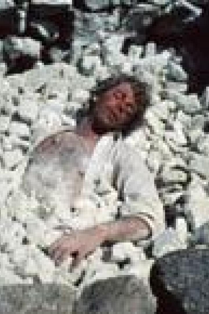 Ein Mann liegt inmitten eines Haufens weißer Steine.