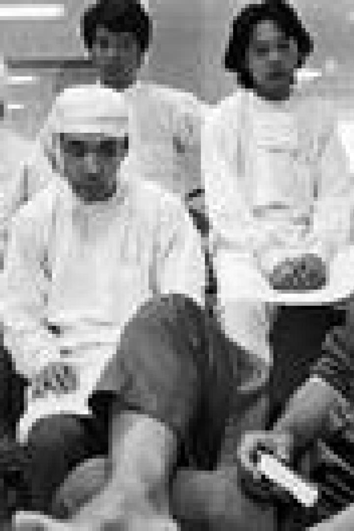 Eine Gruppe von Männern, einige mit Kopfbedeckung, sitzt oder steht in einem Raum.