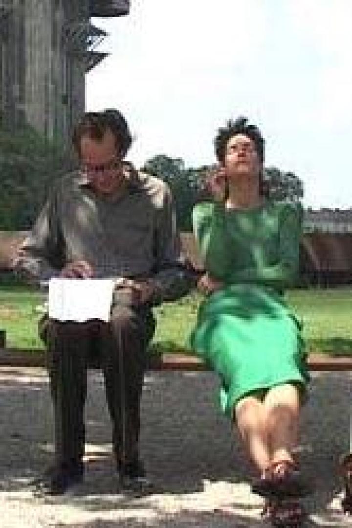 Ein Mann und eine Frau sitzen auf einer Parkbank; die Frau genießt die Sonne.