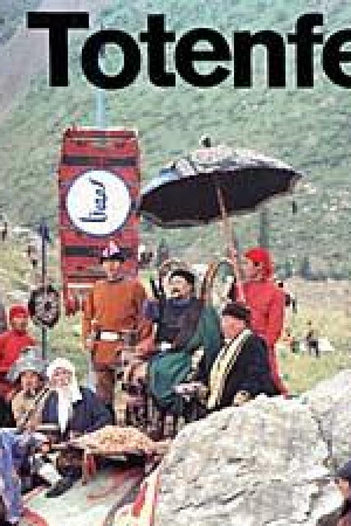 Eine Gruppe von Menschen in traditioneller Kleidung vor einer Bergkulisse bei einer Totenfeier.
