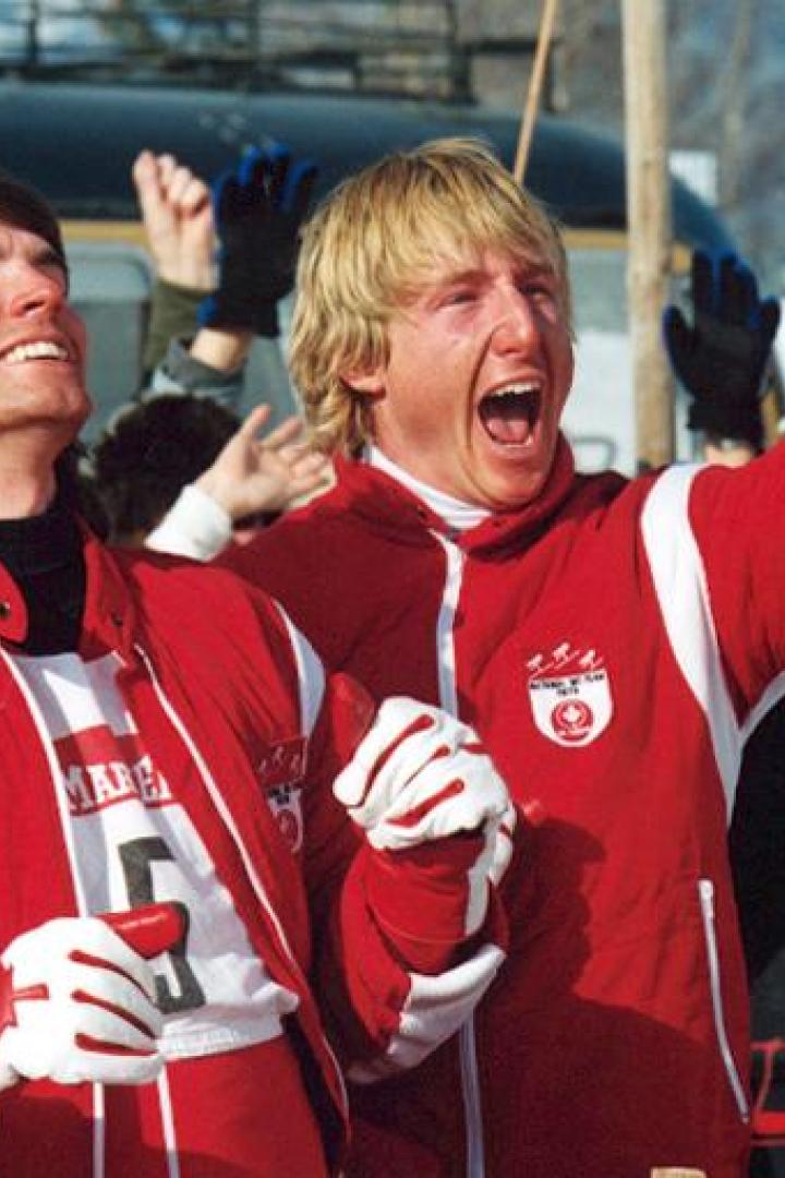 Zwei jubelnde kanadische Skirennläufer in roter Teamkleidung mit einem roten Skihelm.