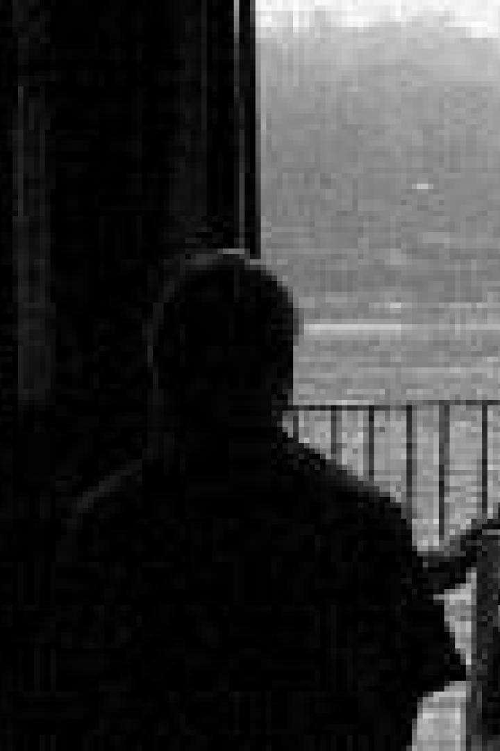 Zwei Personen sitzen auf einem Balkon mit Blick auf einen See.