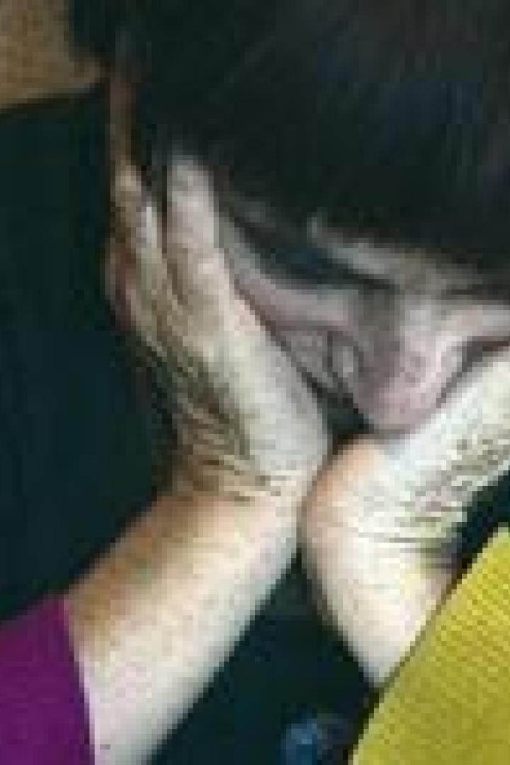 Eine Frau mit roten Haaren stützt ihren Kopf in ihre Hände.