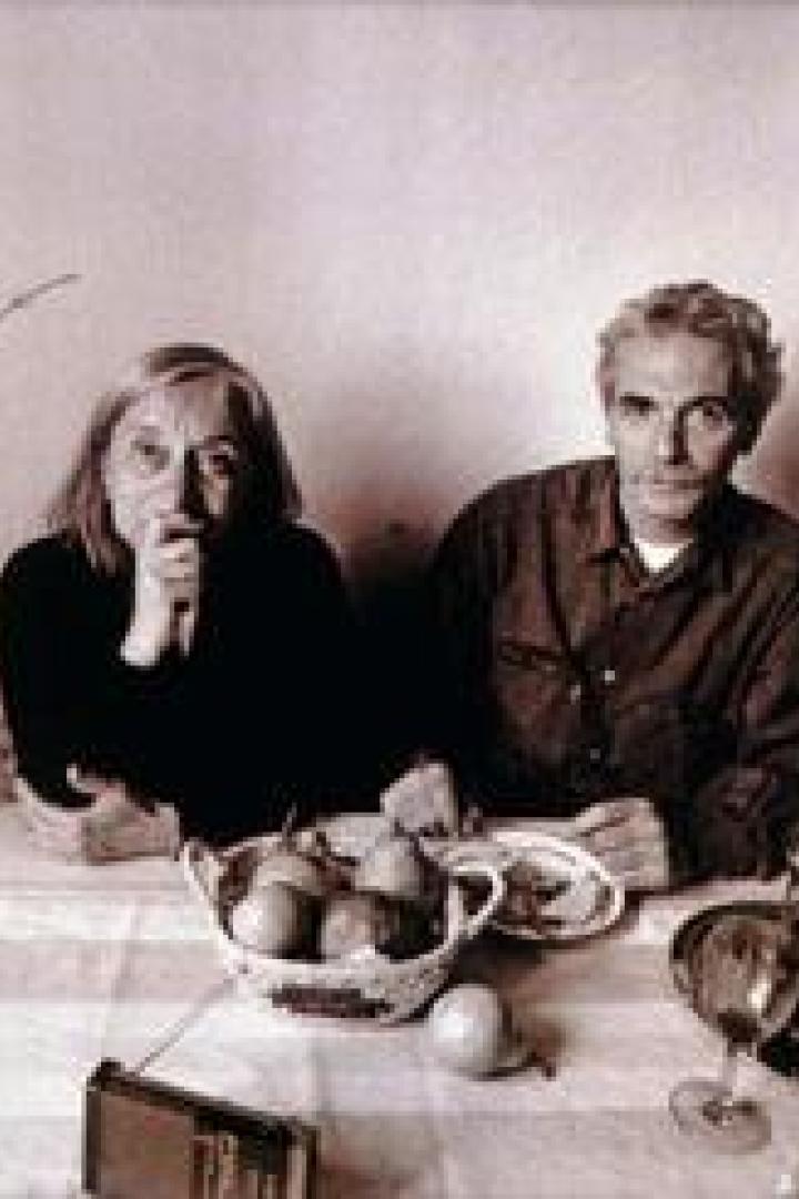 Ein Mann und eine Frau sitzen an einem Tisch mit Obst und Gläsern.