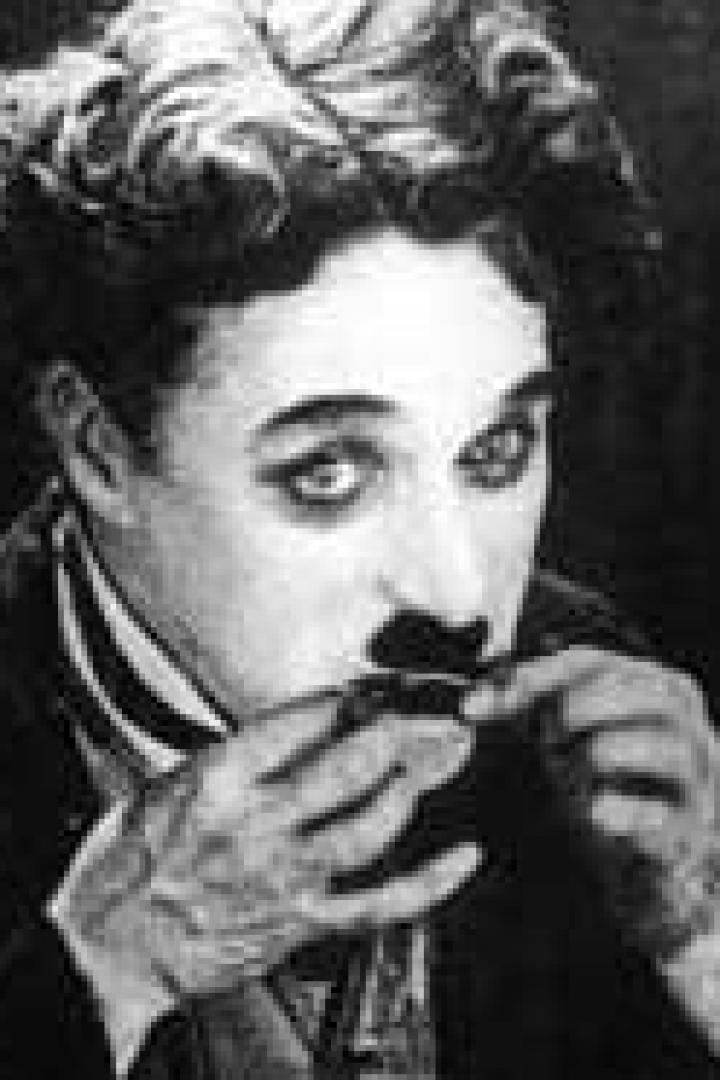 Ein Schwarzweißporträt von Charlie Chaplin, der seinen ikonischen Schnurrbart richtet.
