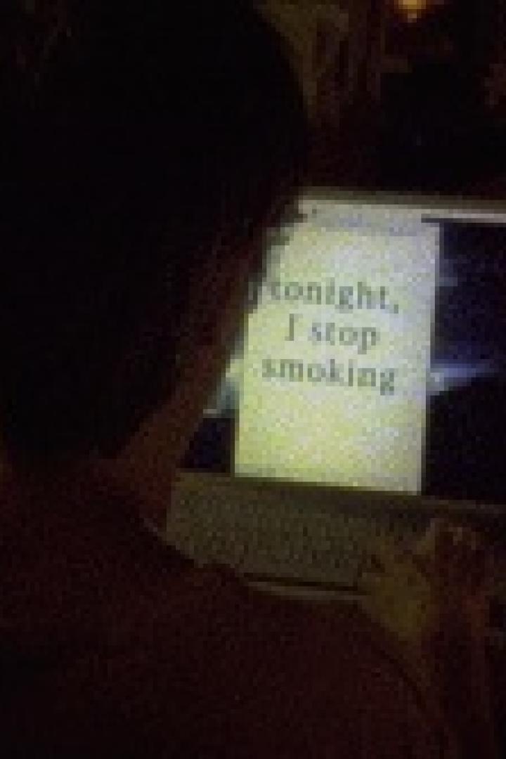Eine Person tippt auf einem Laptop, auf dessen Bildschirm der Text „Tonight, I stop smoking“ zu sehen ist.