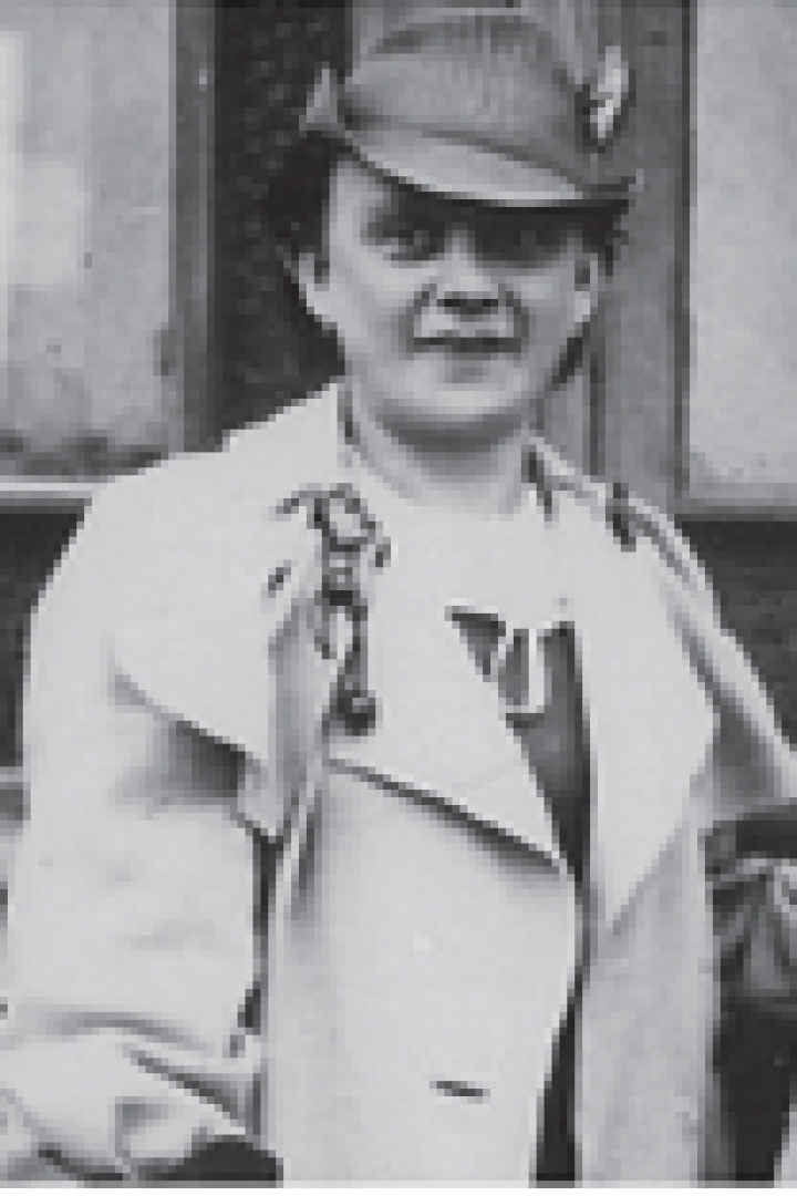 Eine Frau mit Hut und zwei kleinen Mädchen stehen vor einem Fenster.