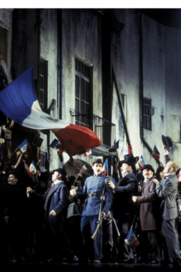 Eine Menschenmenge schwenkt französische Flaggen vor einem Gebäude.