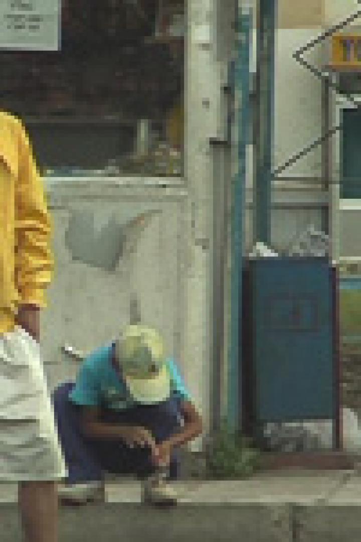 Zwei junge Männer warten an einer Bushaltestelle.