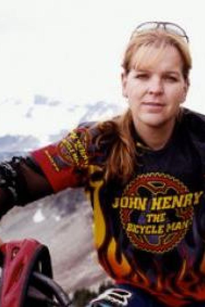 Eine Frau in Sportkleidung posiert vor einer Bergkulisse.