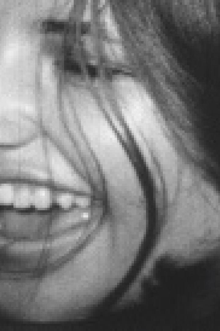 Eine Frau lacht mit geschlossenen Augen und offenem Mund.