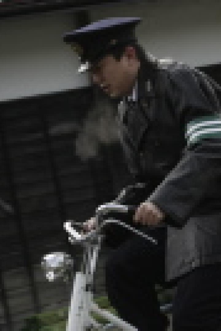 Ein uniformierter Mann fährt mit einem Fahrrad auf einer Straße.