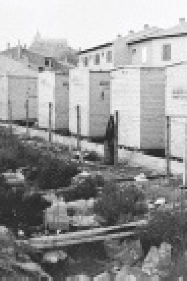 Eine Reihe von kleinen, einfachen Häusern steht entlang eines Bewässerungskanals.