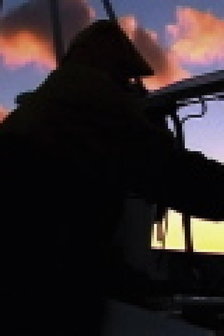 Eine Person steuert ein Segelboot bei Sonnenuntergang.