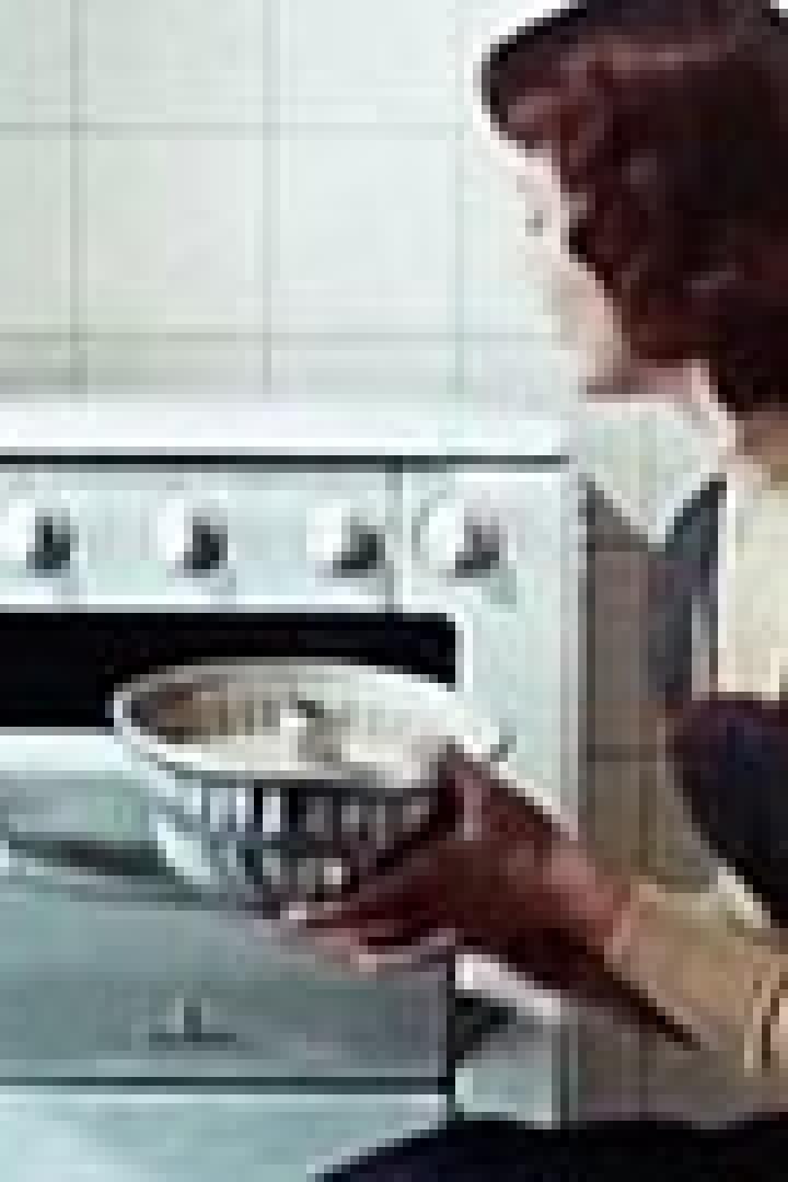 Eine Frau schiebt einen Kuchen in einen Ofen.