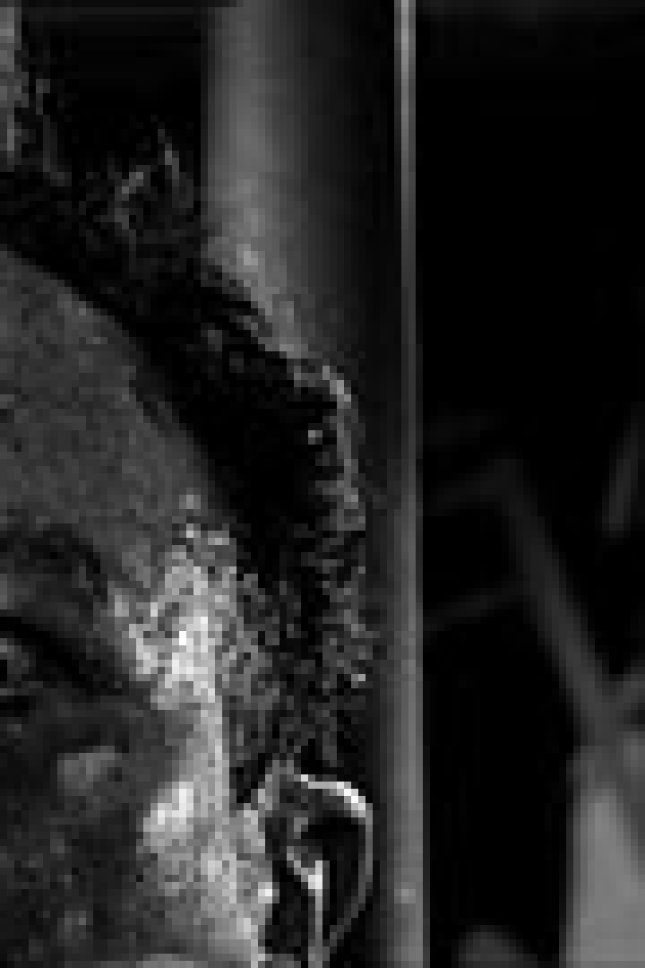 Nahaufnahme eines Mannes mit panischem Gesichtsausdruck, im Hintergrund eine verschwommene, geisterhafte Gestalt.