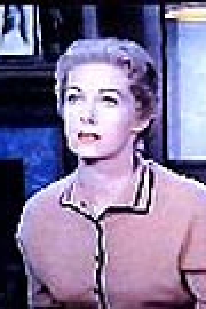 Eine Frau mit blonden Haaren sitzt in einem Sessel und schaut nach oben.