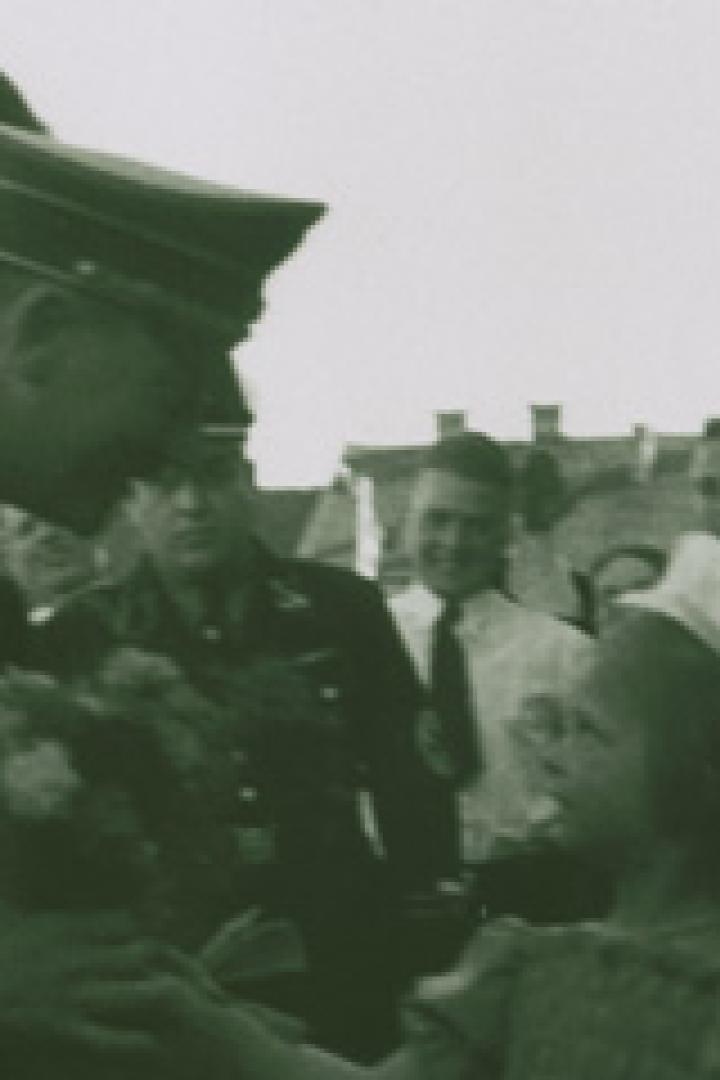 Ein Mann in Uniform überreicht einem kleinen Mädchen einen Blumenstrauß.