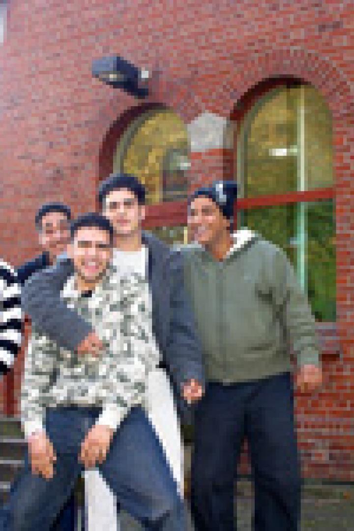 Eine Gruppe junger Männer posiert vor einem Backsteingebäude.